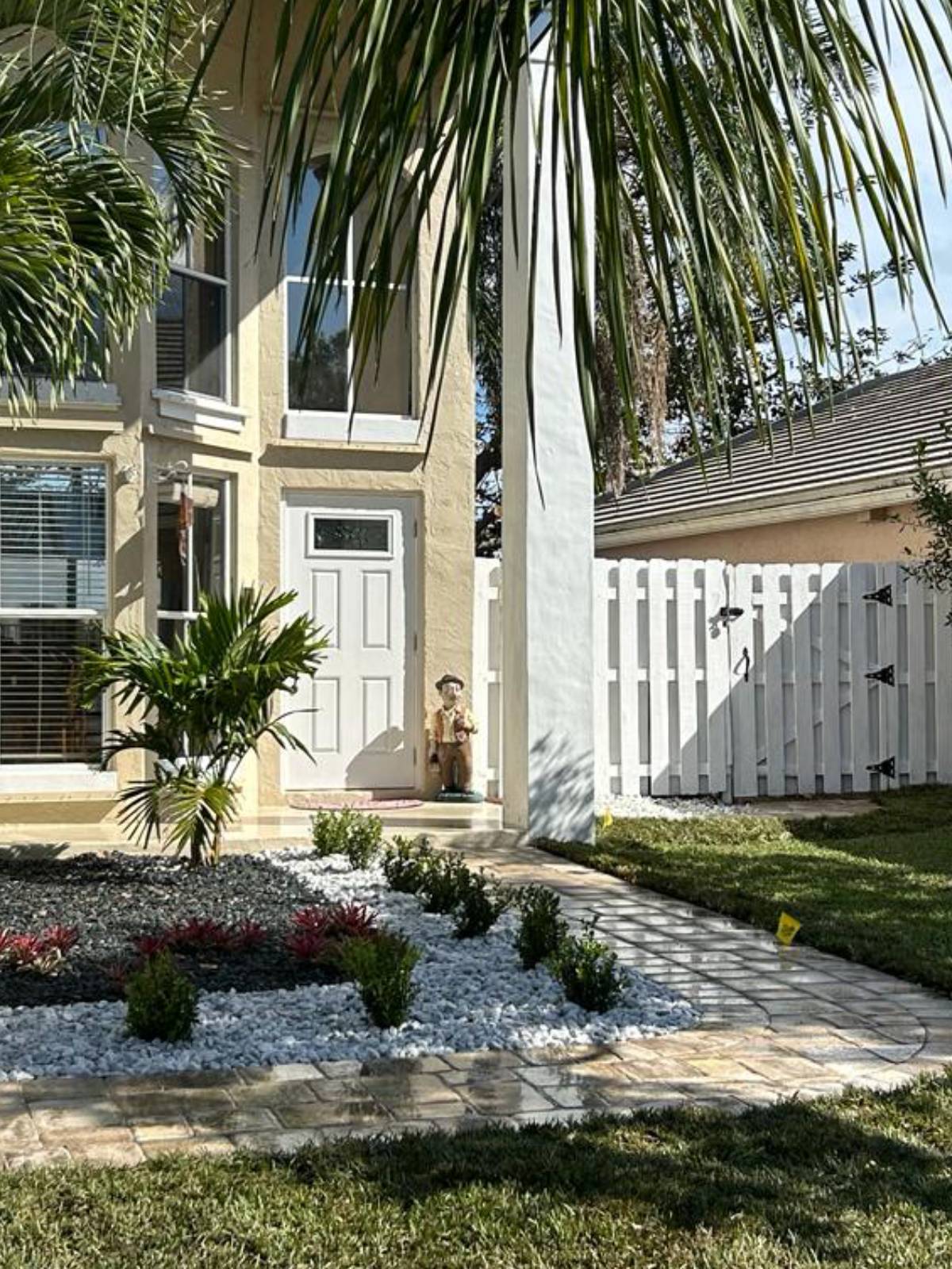 A beautifully landscaped home featuring a lush yard adorned with palm trees.